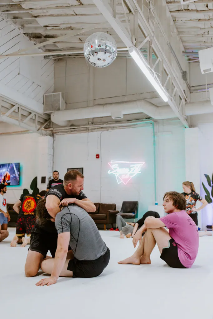 An instructor demonstrates the proper way to execute a guillotine choke during an adult BJJ class at SuperFly BJJ in Decatur, GA.