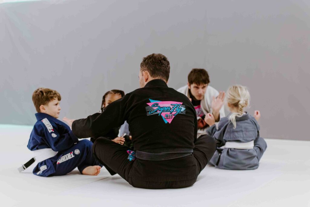 Child learning Brazilian Jiu-Jitsu techniques with supportive coach.