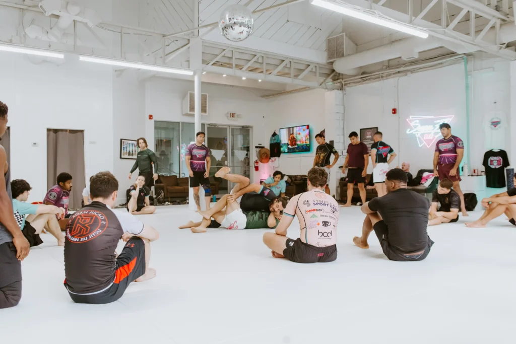 Interior of Superfly BJJ gym in Decatur featuring open mat space, neon signage, and adult martial arts students training,Brazilian Jiu-Jitsu Near Me