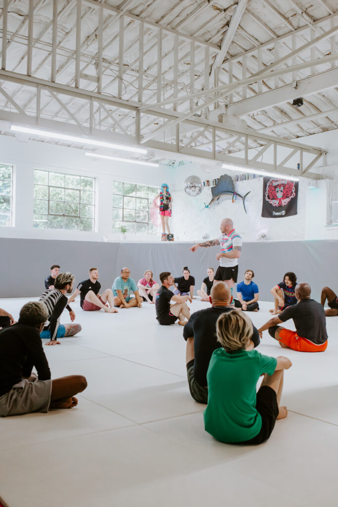 Adult beginners sitting on mats during an Intro to/superfly BJJ 101 class at BJJ in Decatur, Atlanta.