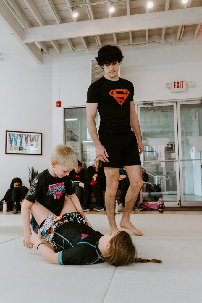 Kids learning Brazilian Jiu-Jitsu techniques with instructor supervision during the Kids 7+ BJJ class at SuperFly BJJ Decatur