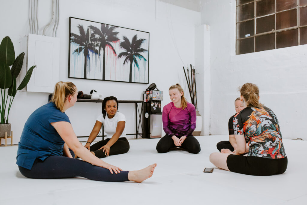 A group of women sitting together before training in the women-only Brazilian Jiu-Jitsu class at SuperFly BJJ Decatur.