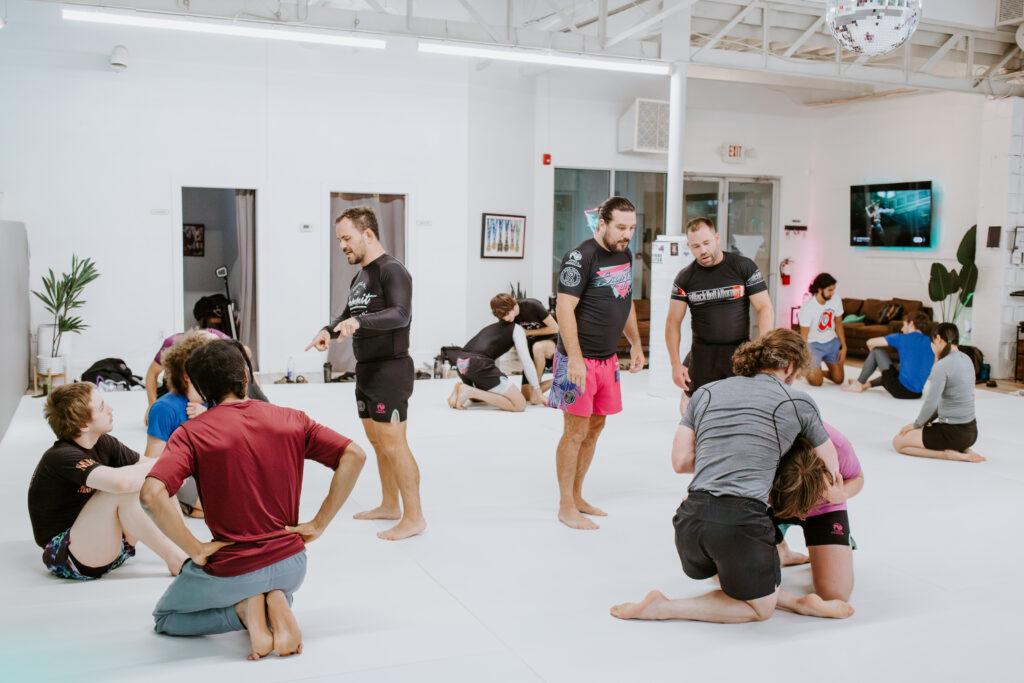 Instructors walking around and helping students during an adult Brazilian jiu-jitsu class at SuperFly BJJ.