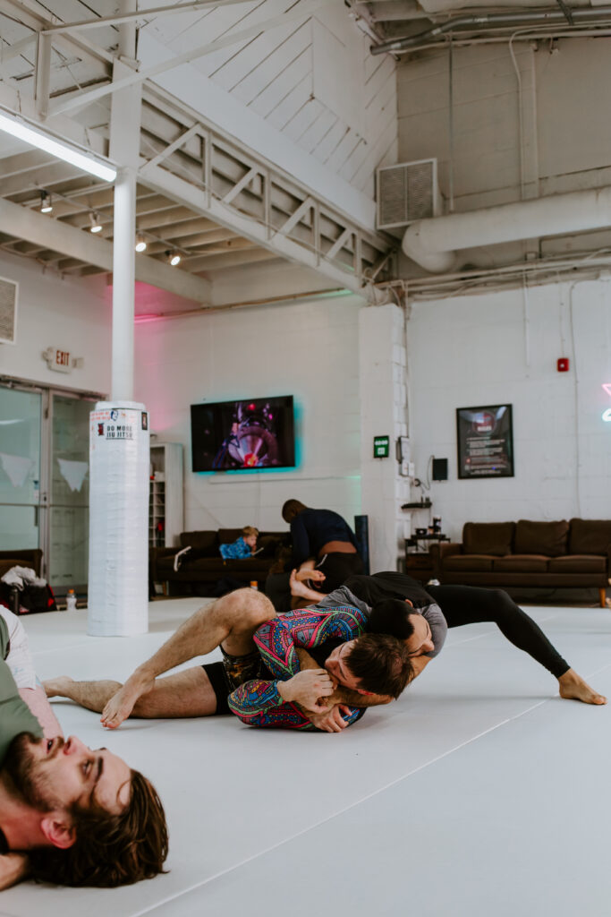 One adult BJJ student is applying a head-and-arm choke to another student during an adult intermediate/advanced no-go bjj class at SuperFly BJJ in Decatur, GA.