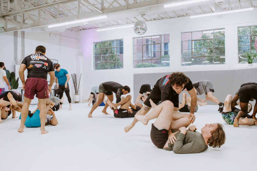 Group of adult brazilian jiu jitsu students drilling techniques during a BJJ class at SuperFly BJJ in Decatur, GA.