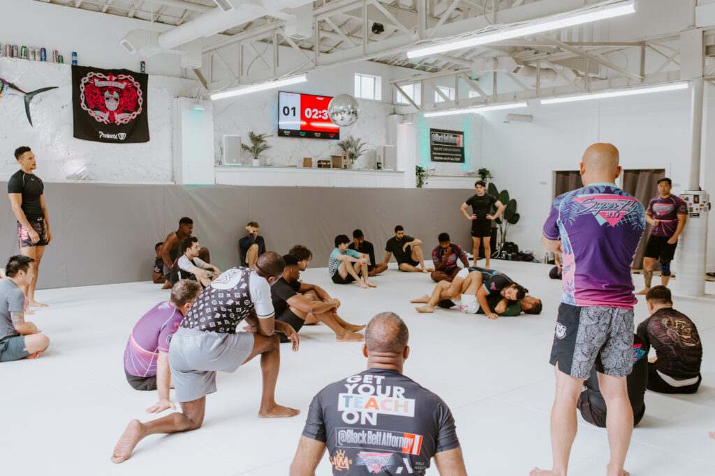 A group of student watch a BJJ coach demonstrate the technique for the evening at an adult BJJ class at SuperFly BJJ in Decatur, GA.